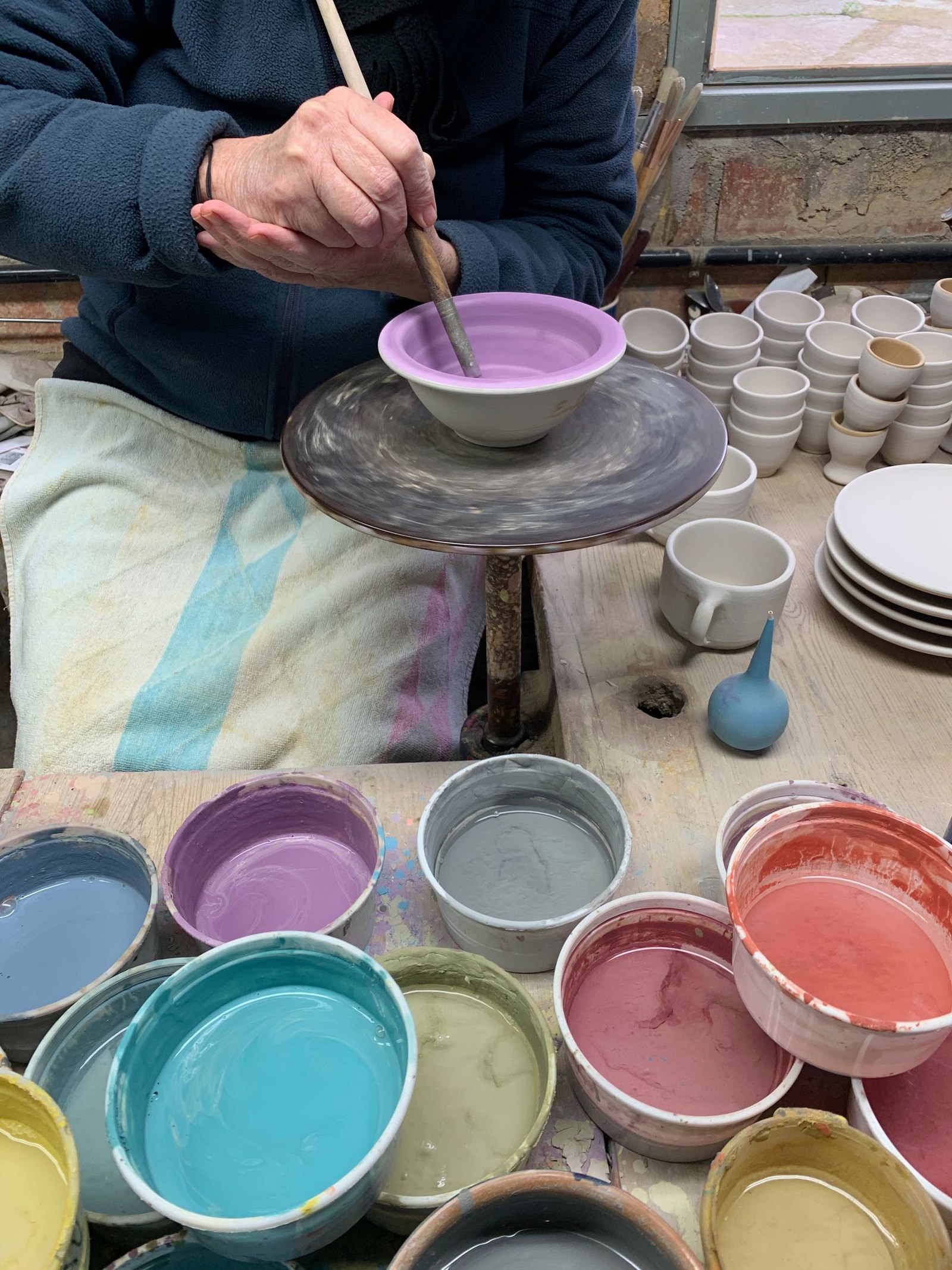 An artist decorating a ceramic bowl with a fine brush