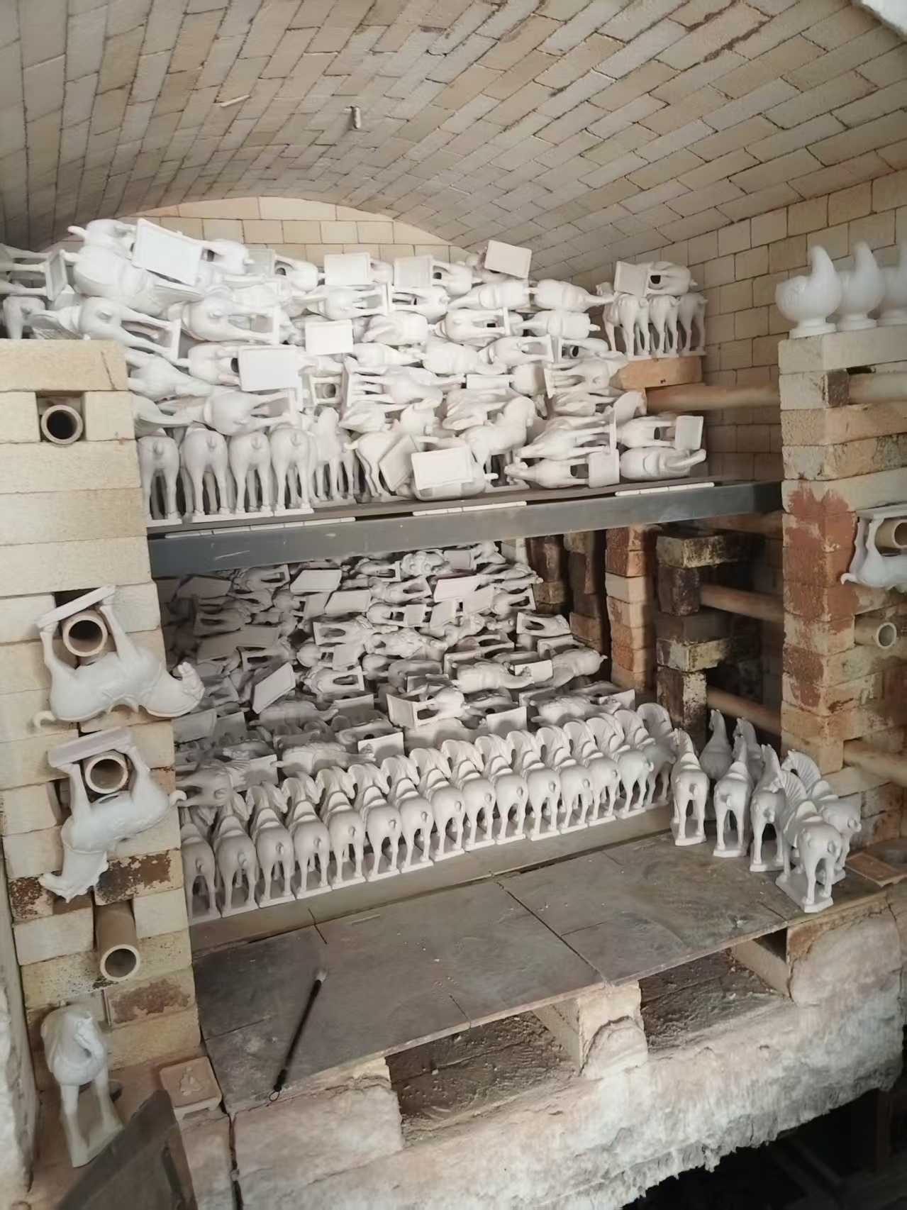 Bisque-fired ceramic pieces standing in a kiln after the first firing