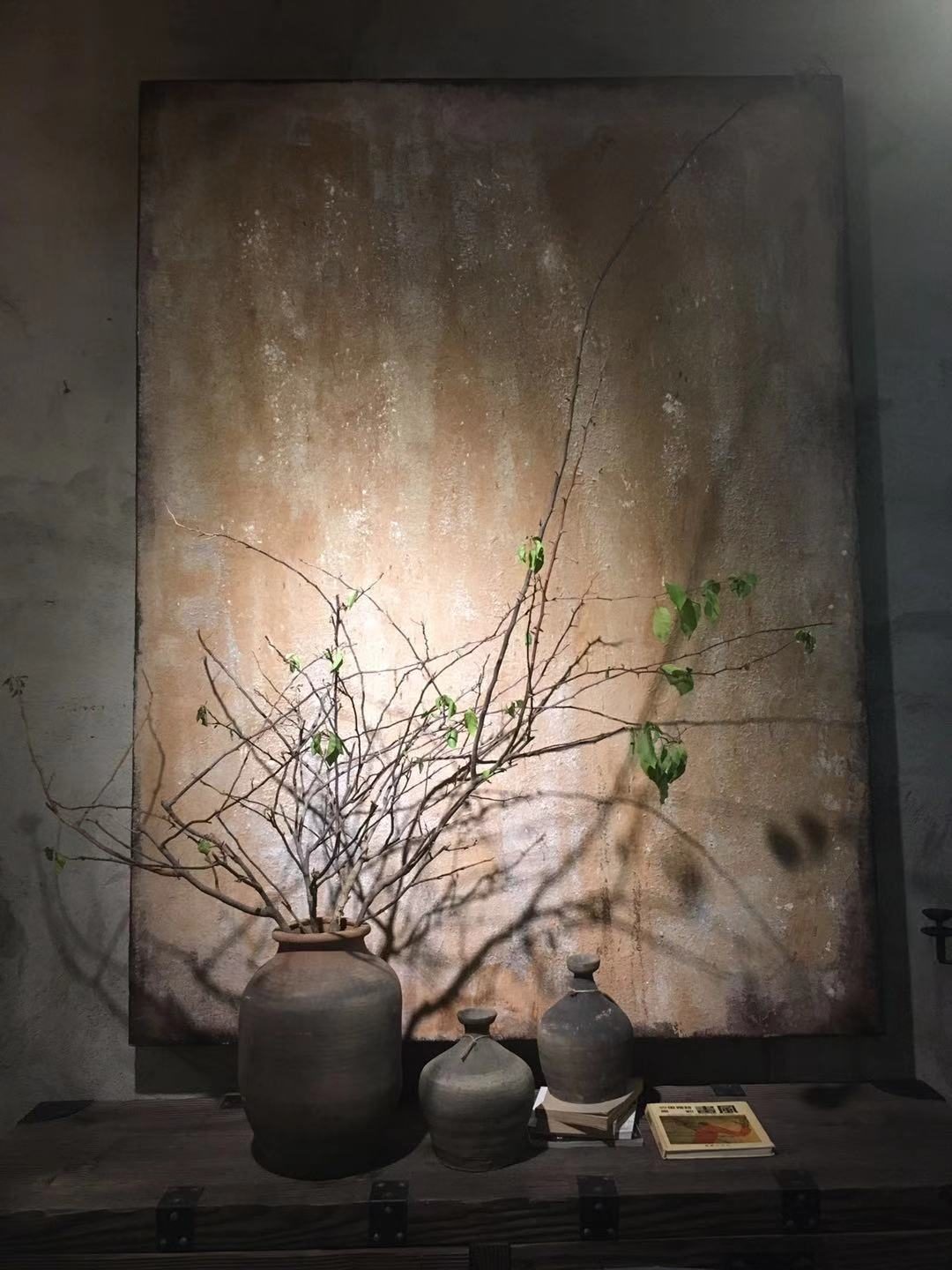 Mineral painting behind a branch arrangement and ceramic vessels