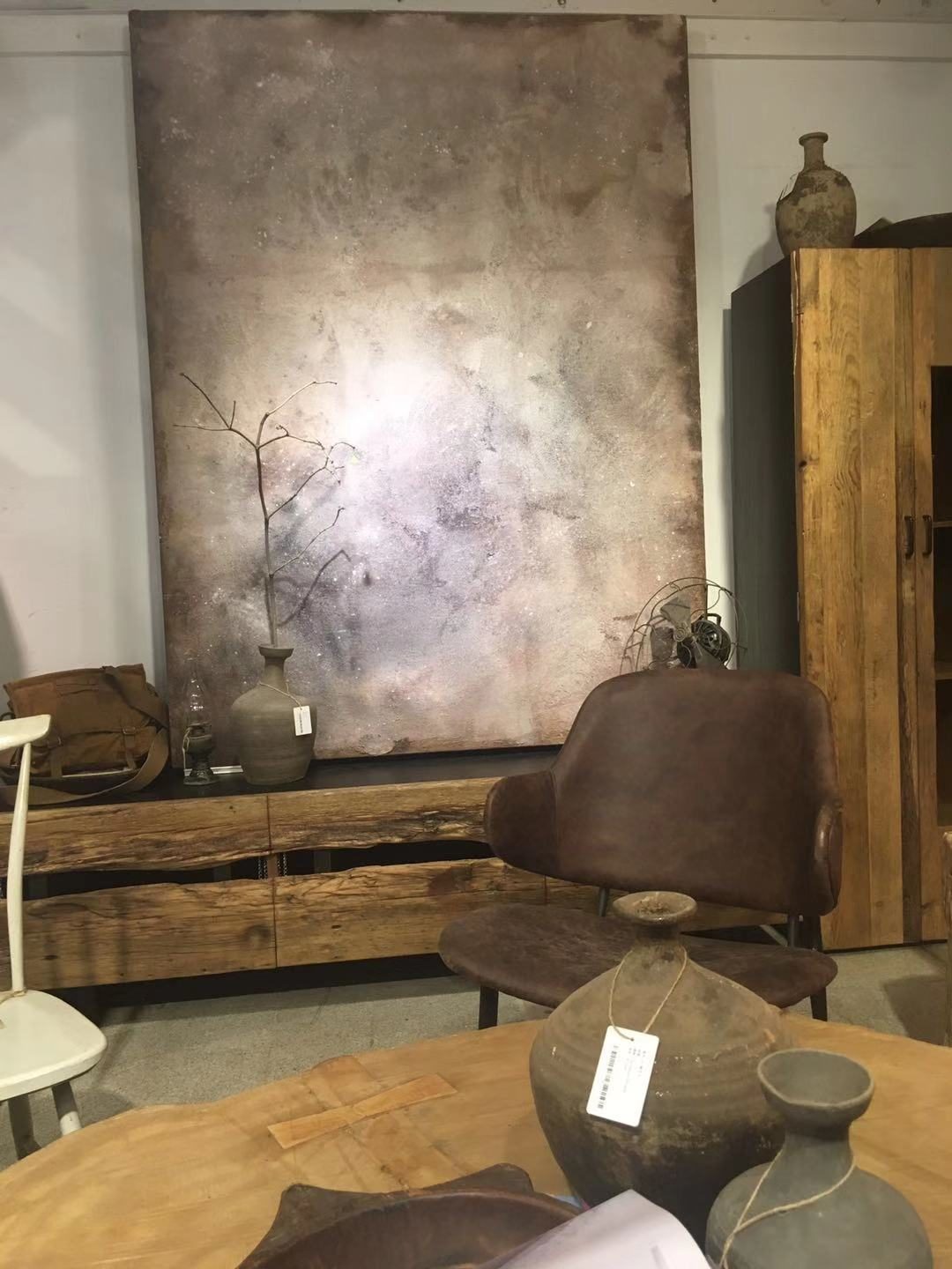 Textured mineral painting lit above a wooden sideboard